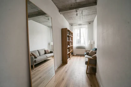 Grand miroir posé contre un mur blanc dans un studio parisien étroit, créant une illusion d'espace et de profondeur